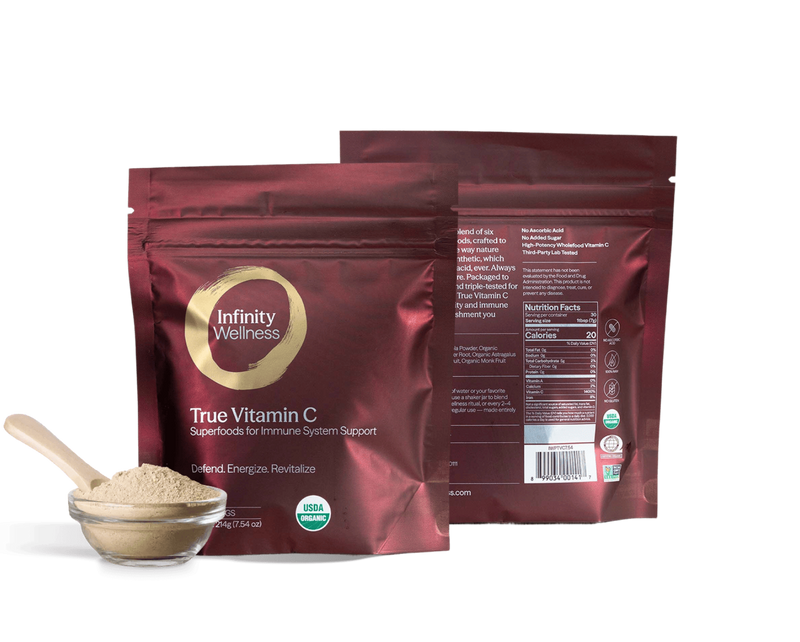 Infinity Wellness True Vitamin C package with a spoonful of powder on a green background